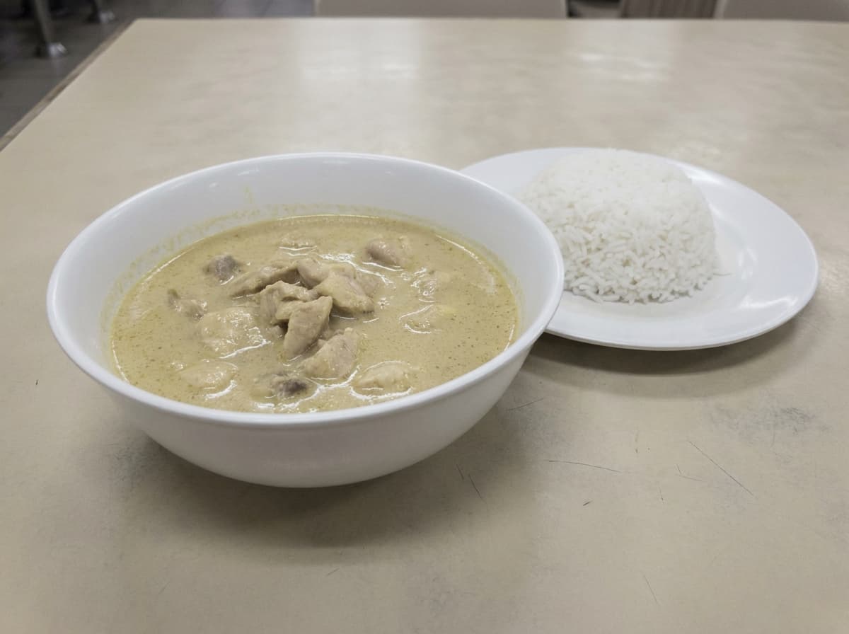 Generic stock-style chicken curry in a plain white bowl on a beige laminate table